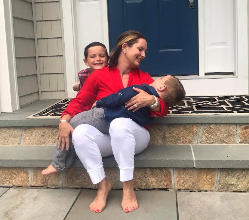 A woman holding her little boy in her lap with the other child resting his head on her shoulder from...