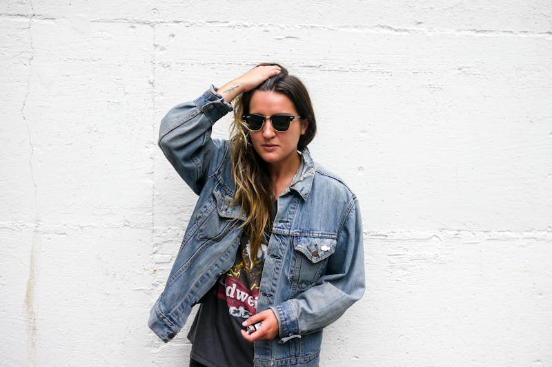 A woman posing with her hand running through her hair in a denim jacket