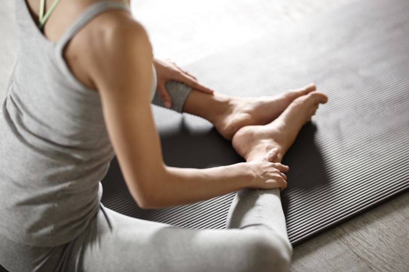 A woman practices yoga in a grey sports outfit