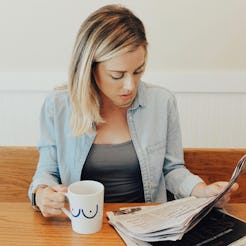 A woman with a BRCA Diagnosis reading a newspaper while drinking coffee