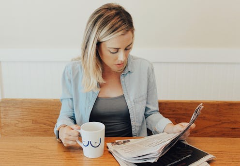 A woman with a BRCA Diagnosis reading a newspaper while drinking coffee
