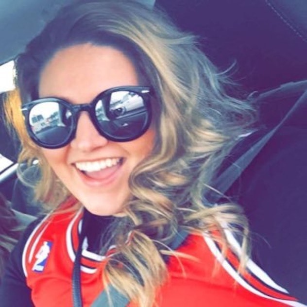 A woman in a red jersey and with sunglasses, smiling and taking a selfie