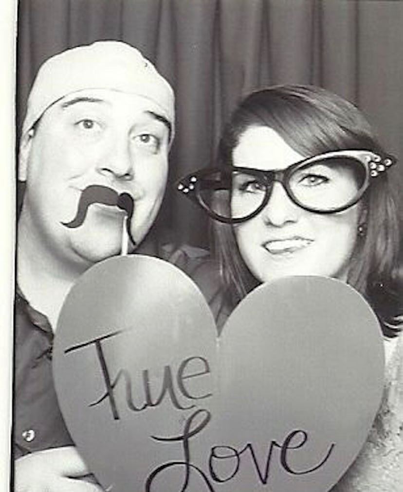 A couple posing with a heart-shaped paper with "true love" text