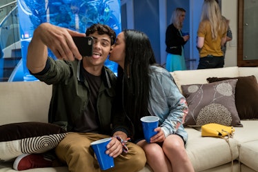 Peter and Lara from 'To All the Boys I've Loved Before' take a selfie on a couch at a party.