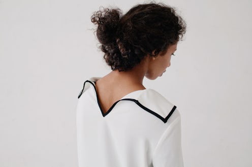 A girl with arthritis standing while wearing a white shirt