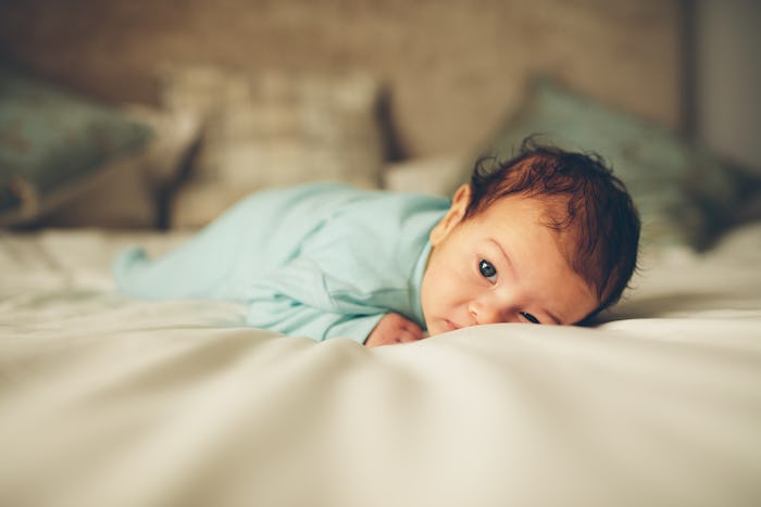 A baby whose name starts with Q lying on a bed on its tummy 