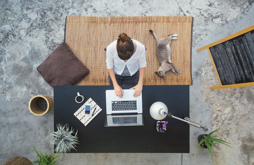 A top down view of a woman at her desk working on her laptop preparing herself for stressful situati...