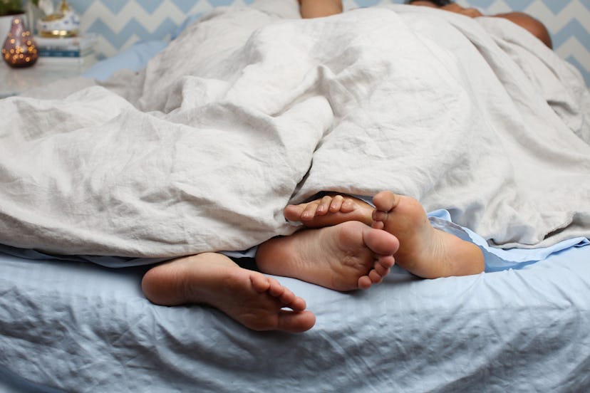 A couple having sex under a white blanket