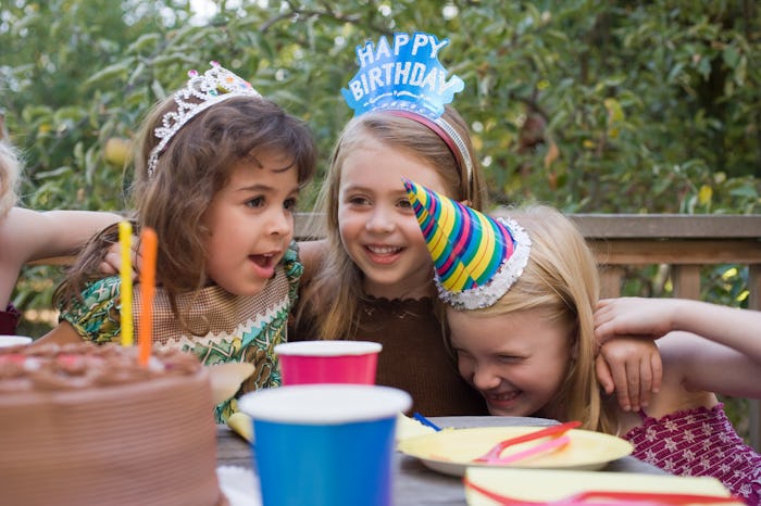 Three girls wearing birthday decorations on their heads hugging