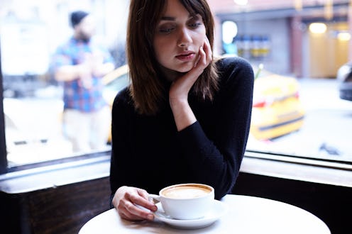 A woman sitting in the corner booth of a cafe with a late in front of her