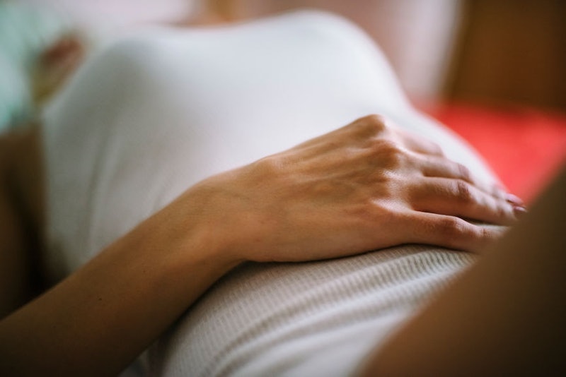 A woman feeling symptoms of endometriosis lying while holding her hand on her stomach