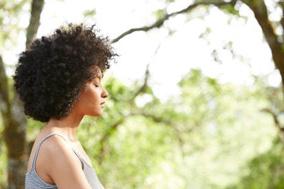 A woman with curly hair with her eyes closed in the nature