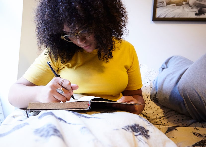 A woman experiencing numbness and tingling writing something in a notebook while lying in bed