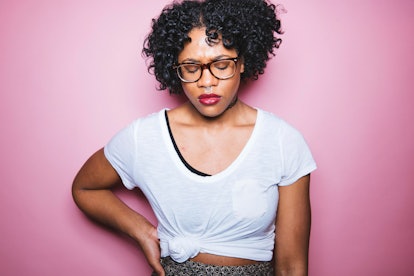 A woman in a white shirt holding her side in pain while on anti-seizure drugs