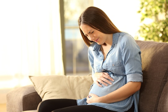pregnant woman in pain holding belly on couch