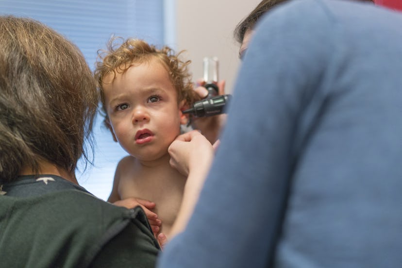 A kid getting his ear checked by a doctor due to an ear infection