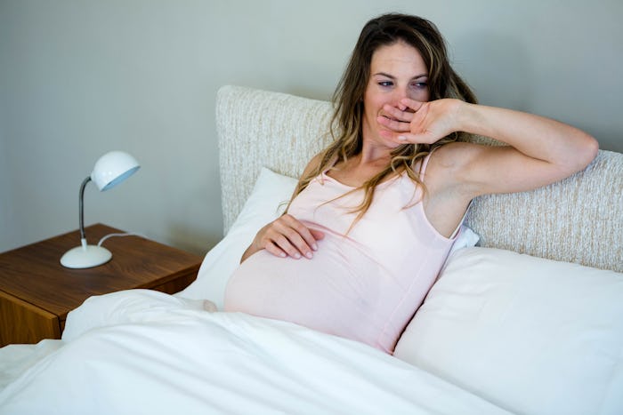 Pregnant woman waking up in bed in the morning 