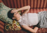 A woman with headache lying on the sofa and holding her head 