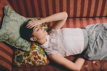 A woman with headache lying on the sofa and holding her head 