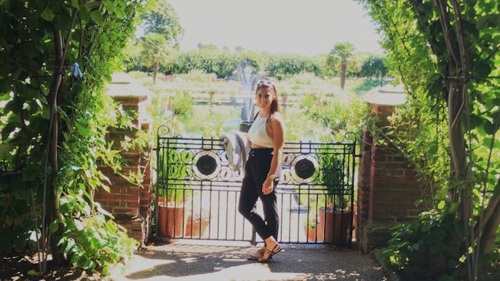 A woman who cannot get pregnant, in a white cropped tank and black pants posing at the front gate of...