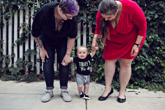  Dese'Rae L. Stage and her partner holding hands with their baby while he's standing