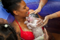 A mom holding her newborn right after a waterbirth with a doula's help