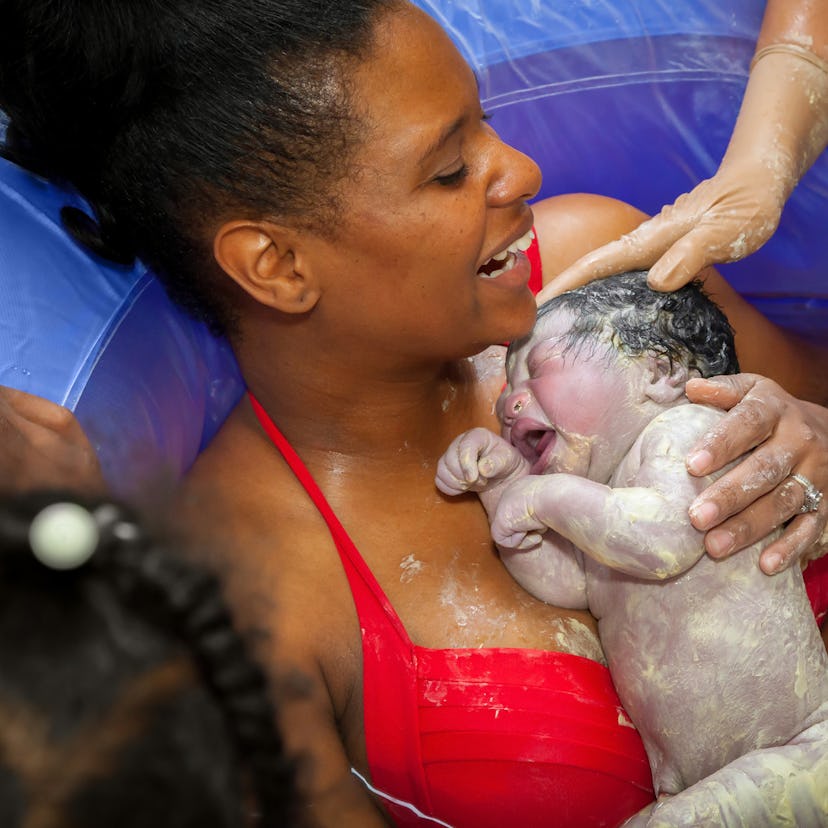 A mom holding her newborn right after a waterbirth with a doula's help