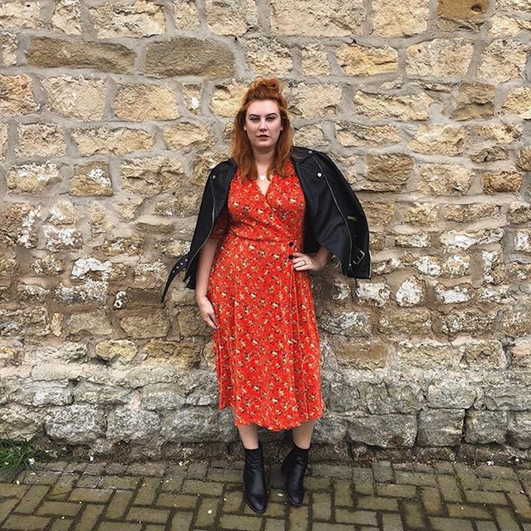 Plus-Size Influencer wearing a orange dress and black leather jacket over her shoulders.