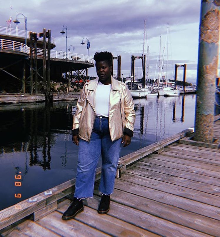 Plus-Size Influencer Lydia Okello posing in gold leather jacket on the dock.