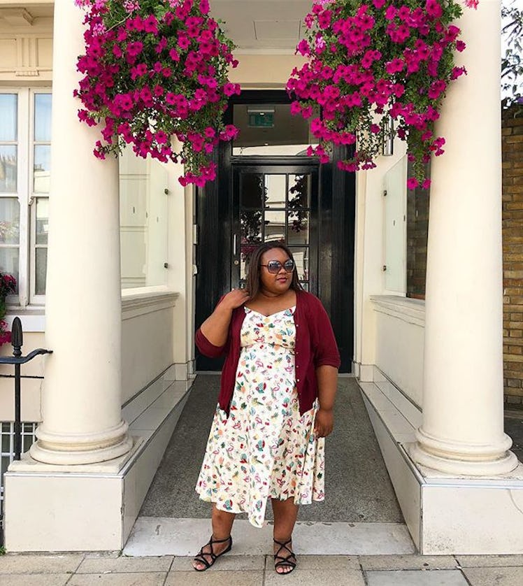 Plus-Size Influencer Isha Reid wearing a white dress while posing in front of door entrance.