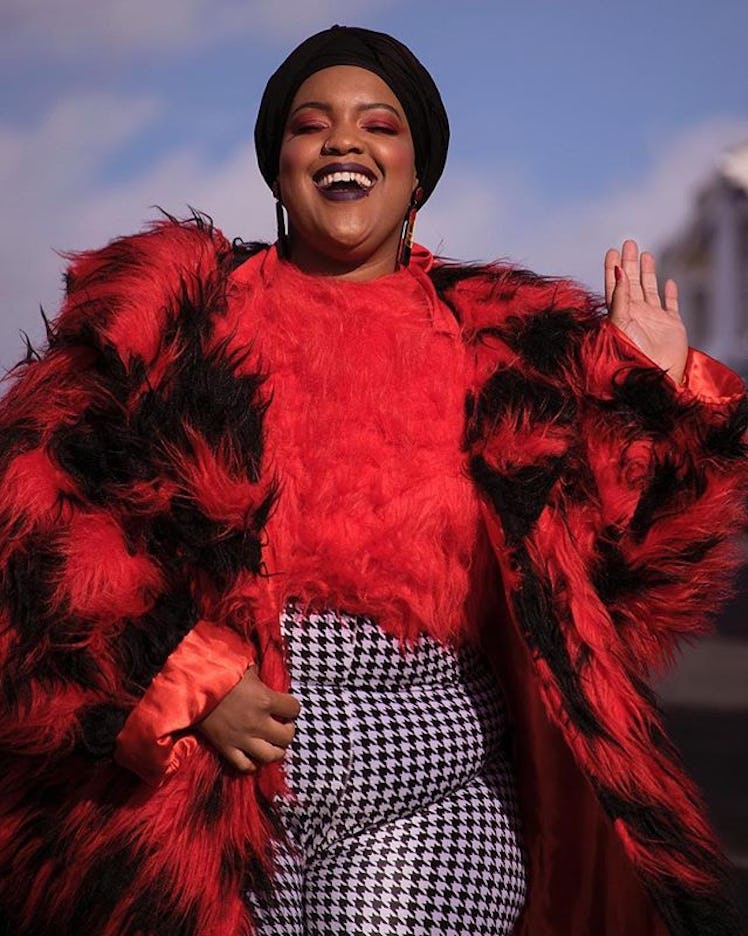 Plus-Size Influencer Leah Vernon posing while wearing a red furry coat over a red furry sweater.