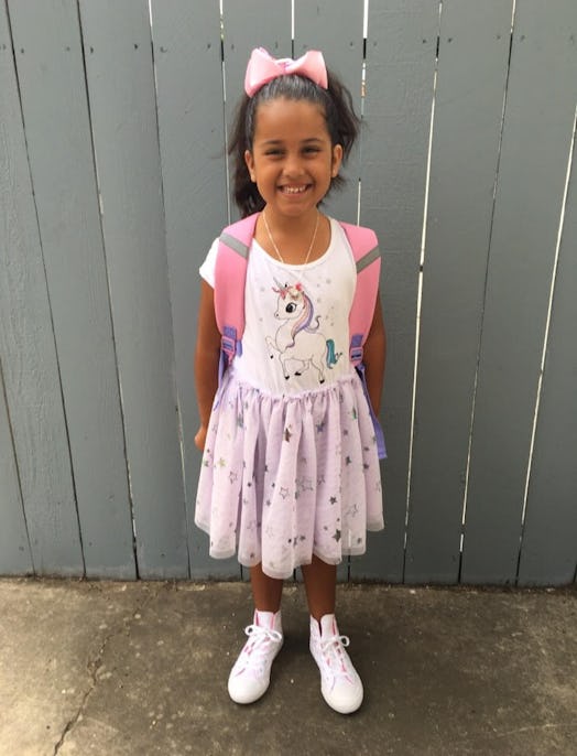 A Kristen's daughter posing for a picture in her unicorn dress and with a pink backpack 