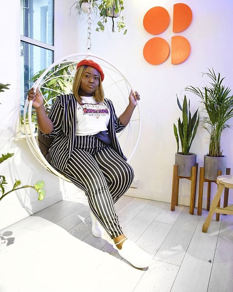 Plus-Size Influencer Dennetta Mckain posing while wearing a striped suit and red beret.