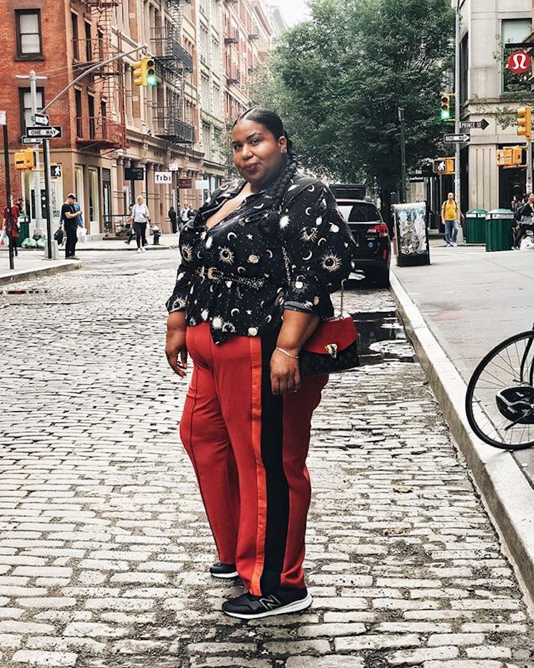 Plus-Size Influencer Kellie Brown posing in red pants with black astrology detailed shirt. 