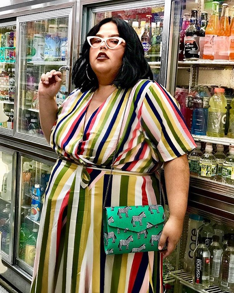 Plus-Size Influencer Jessica Torres posing in colorful dress in front of beverage fridge.