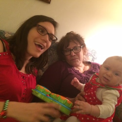 A newborn baby sitting next to its mother and grandmother