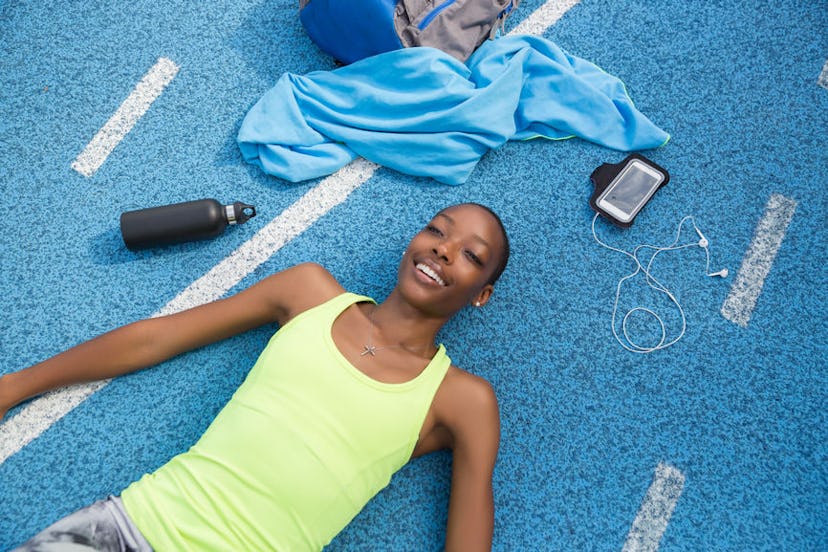 A woman lying on the ground after an intense workout who has a headache