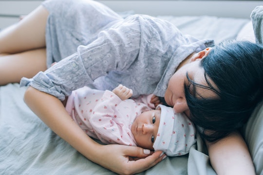 Woman with mom burnout is lying in bed cuddling with her baby