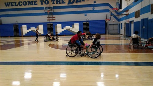 People in wheelchairs at a Wauwatosa basketball court during  basketball practice