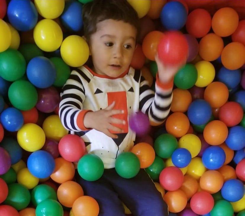 A boy playing with the colorful plastic balls