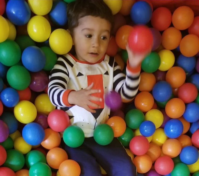 A boy playing with the colorful plastic balls