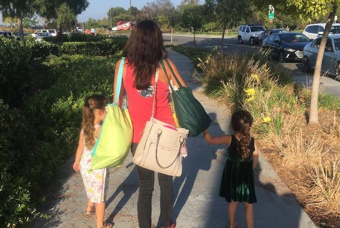 The back of Ambrosia Brody walking on a pedestrian with her two kids