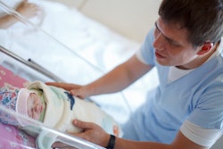 A father looking at his newborn baby sleeping in the hospital