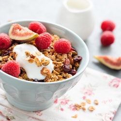A bowl of granola with raspberries, figs and yogurt.