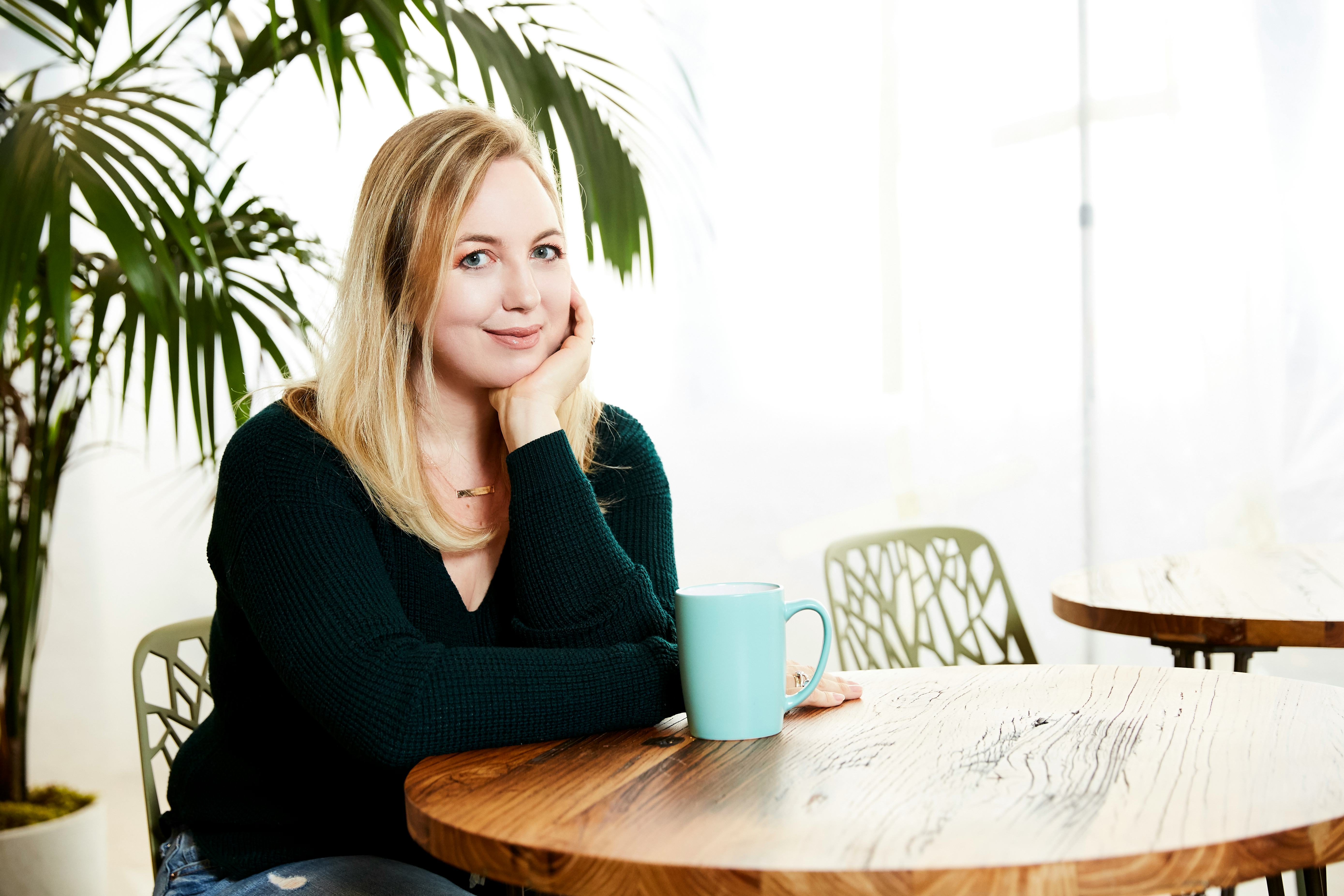 A woman smiling and sitting on a chair next to a table who is prepared for motherhood