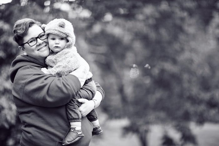 Dese'Rae L. Stage holding her baby wearing a teddy coat, smiling for a photo