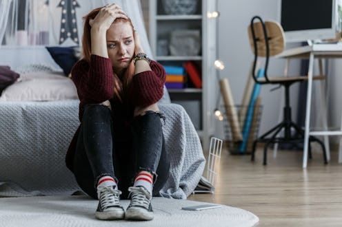 A worried woman sitting on the floor because of having signs of cancer