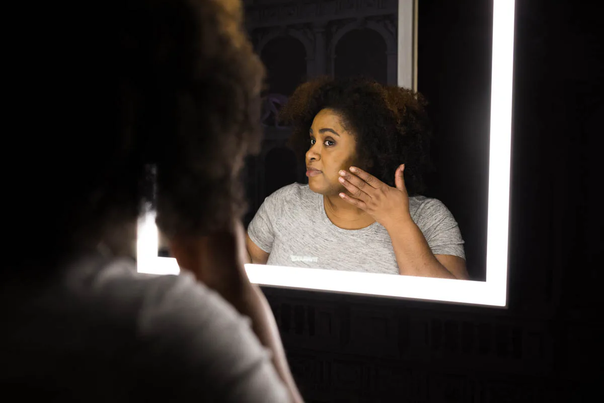 A girl that has gum bleeding looking herself in the mirror