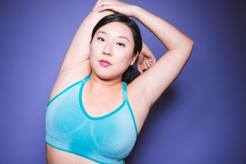 A woman stretching her shoulder and elbow in a blue sports bra