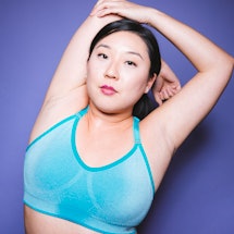 A woman stretching her shoulder and elbow in a blue sports bra